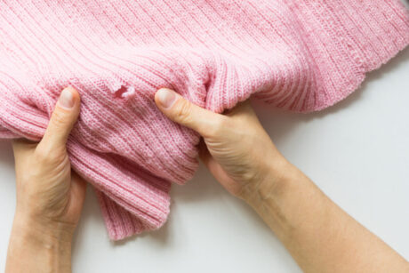 Woman hands holding the knitted thing with hole made by mole